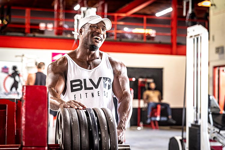A member resting his hands on a stack of weight plates at Boulevard Fitness